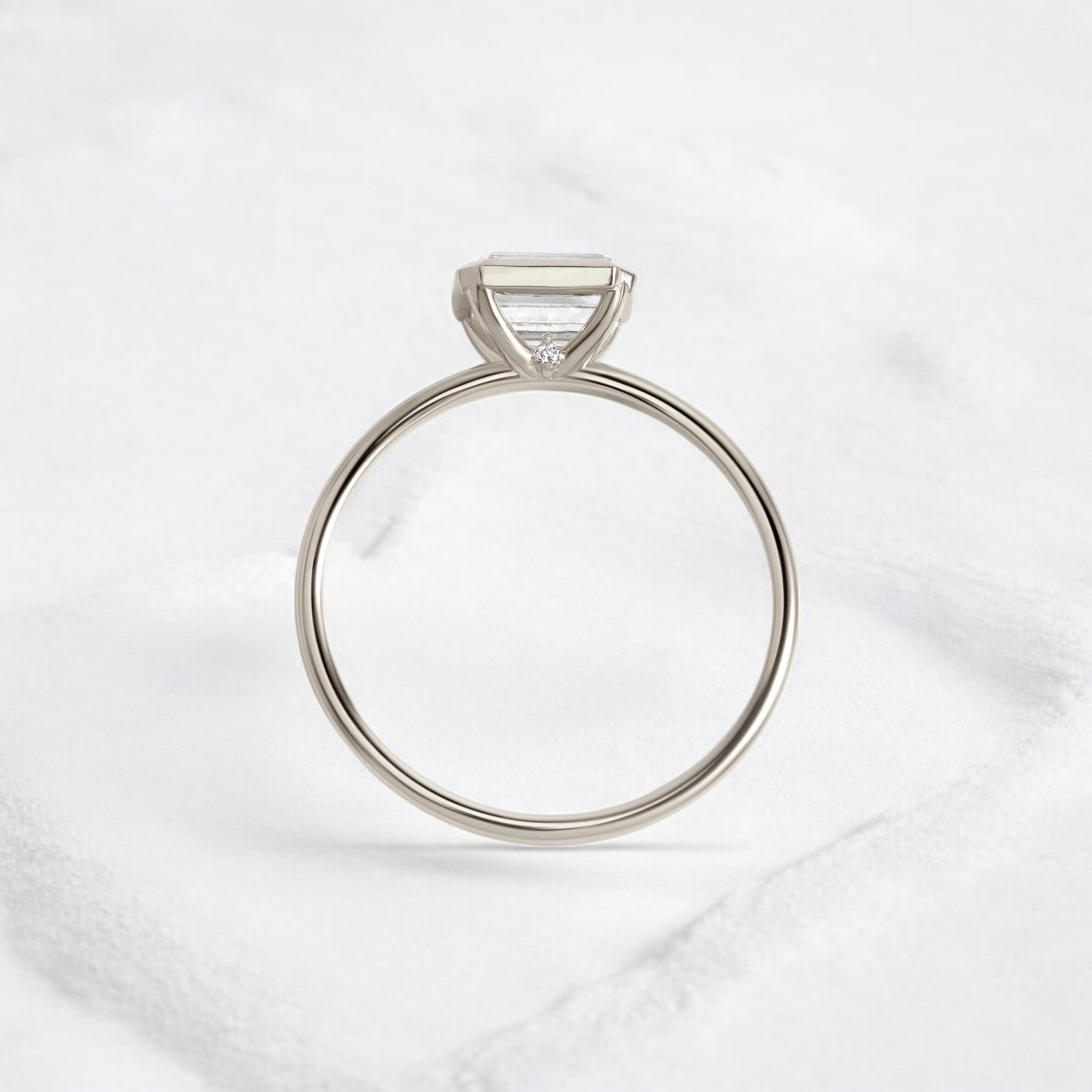 Elegant handmade emerald cut diamond engagement ring, featuring a bezel setting designed for women.