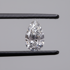 Pear-shaped diamond held between tweezers against a gray background