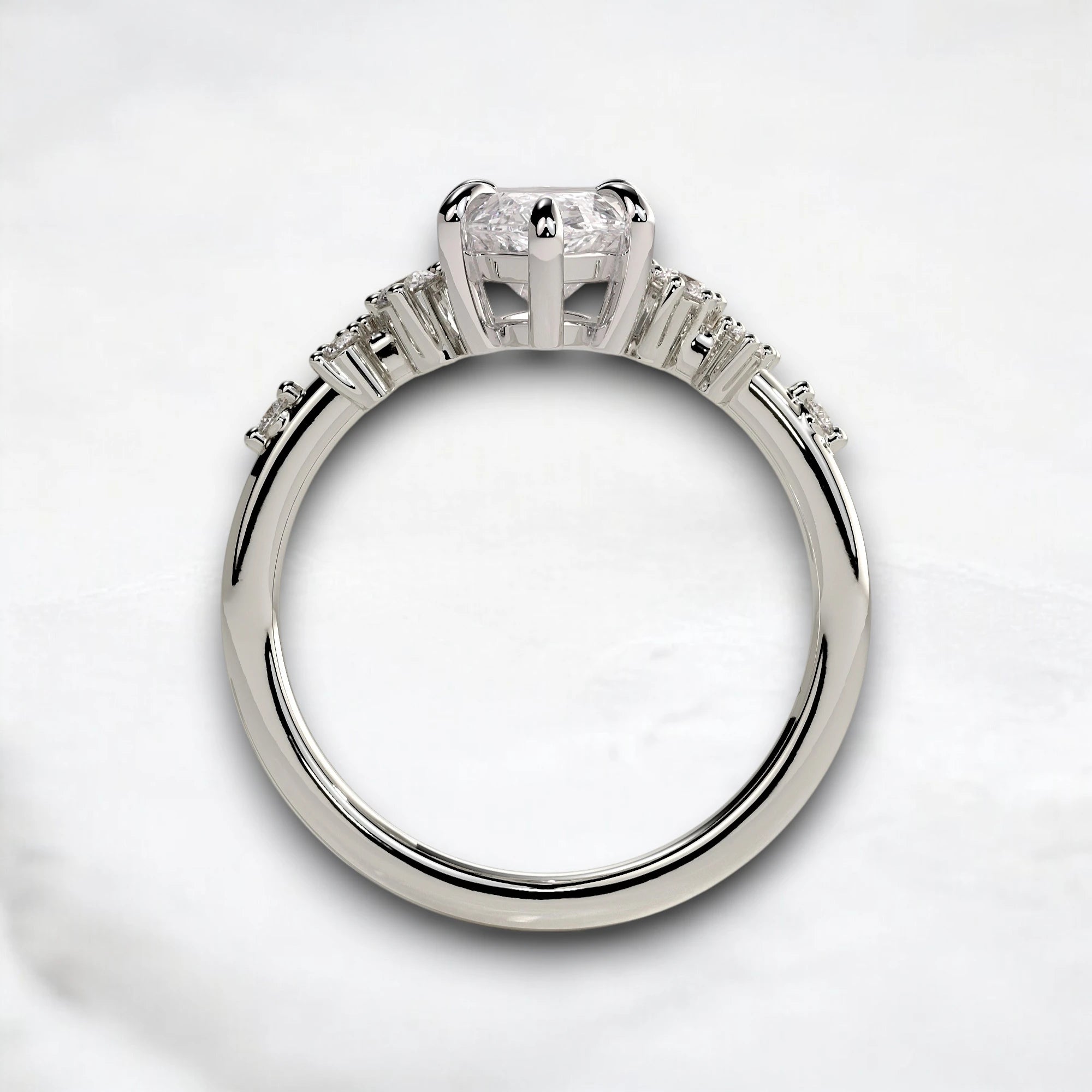 A silver-toned diamond ring with a large round-cut center stone and smaller side stones, photographed on a light marble-like surface.