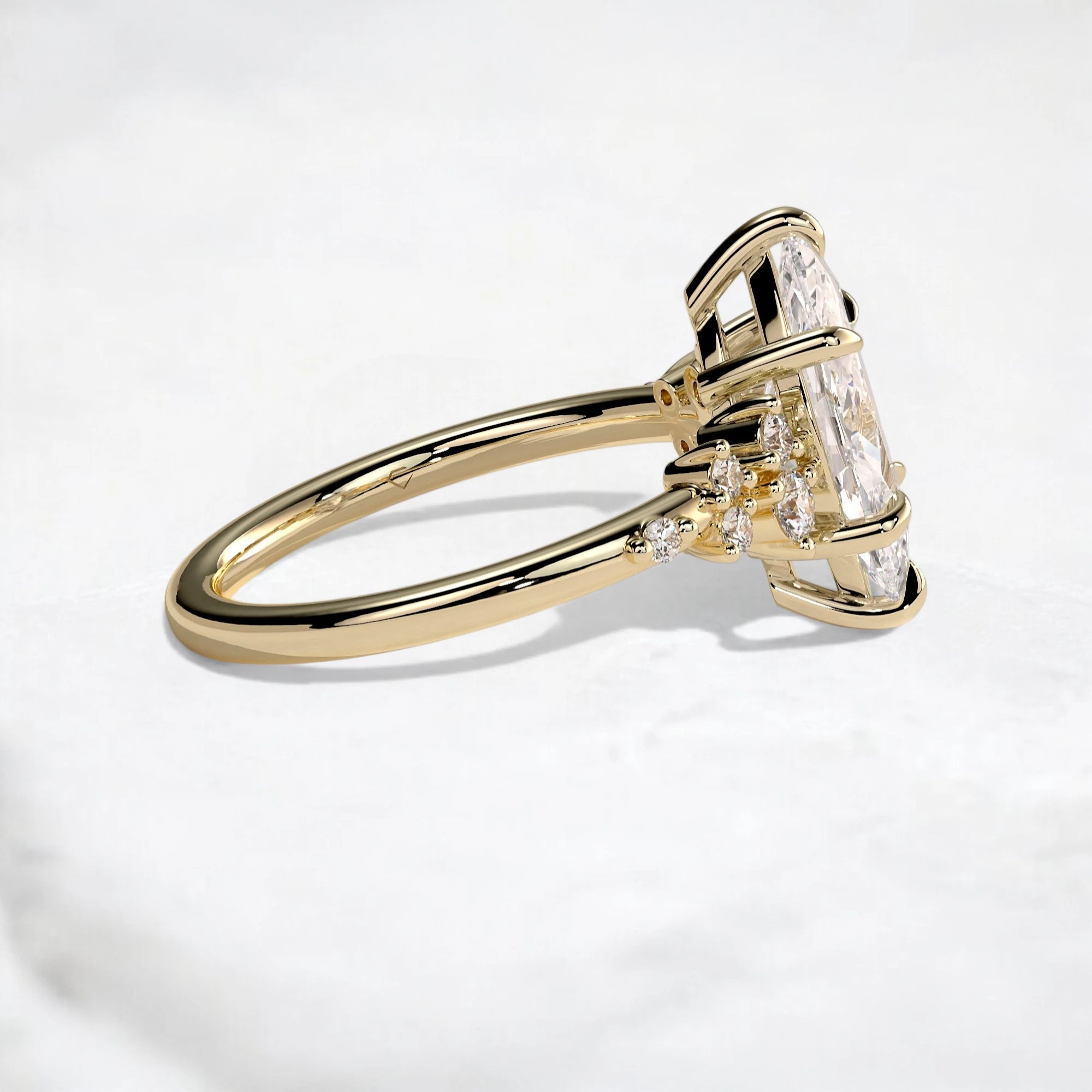 A yellow gold ring featuring a large rectangular clear gemstone in a prong setting, accented by smaller round stones on the band, photographed on a light gray marble surface.