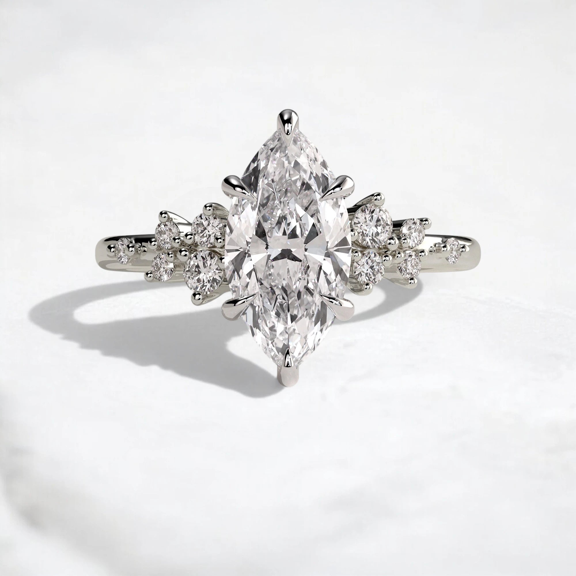 A silver-tone ring featuring a large marquise-cut clear center stone with smaller round stones set along the shoulders, photographed on a clean white surface.