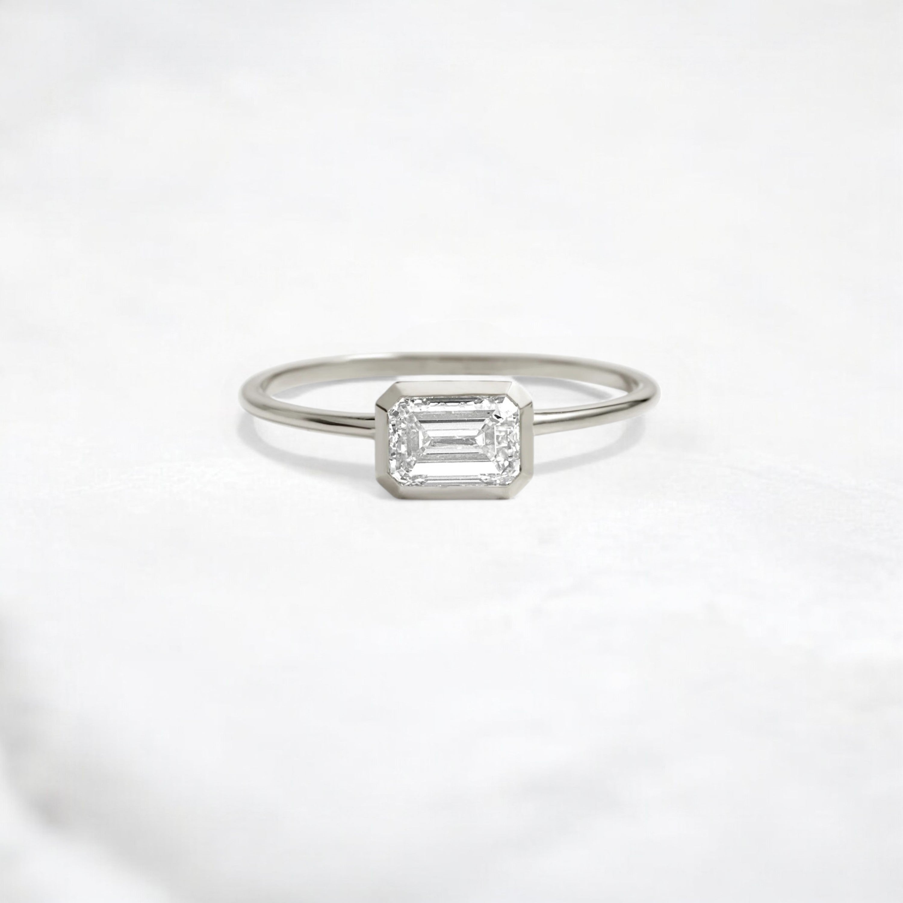 Elegant handmade emerald cut diamond engagement ring, featuring a bezel setting designed for women.