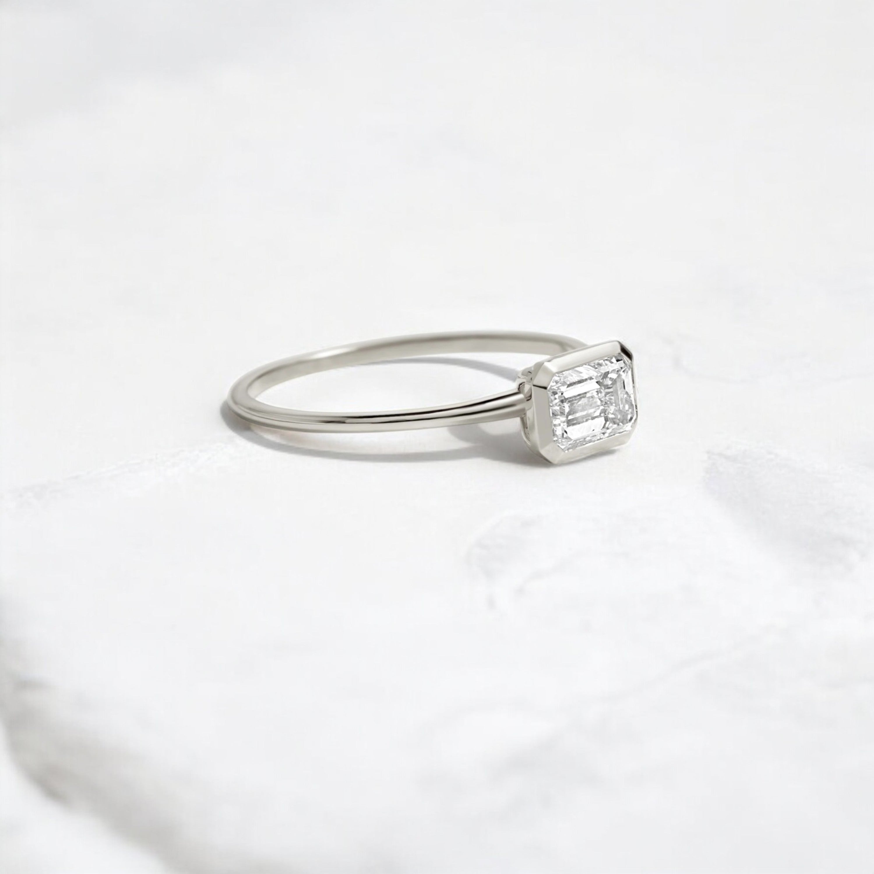 Elegant handmade emerald cut diamond engagement ring, featuring a bezel setting designed for women.