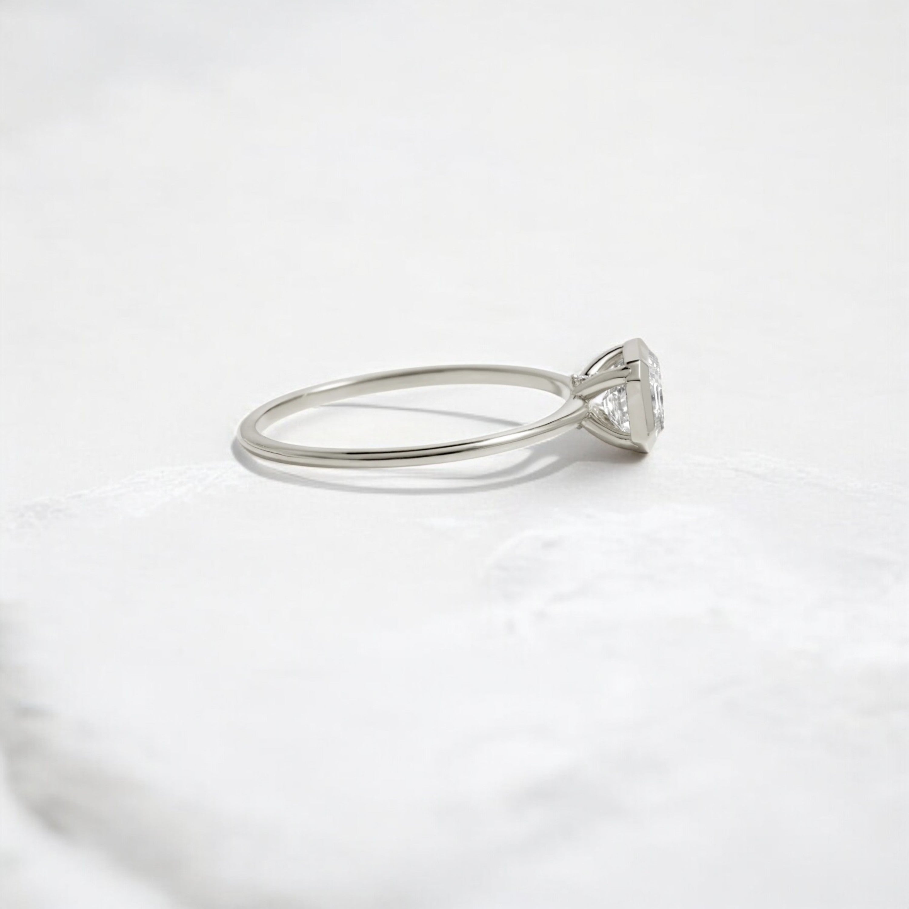Elegant handmade emerald cut diamond engagement ring, featuring a bezel setting designed for women.