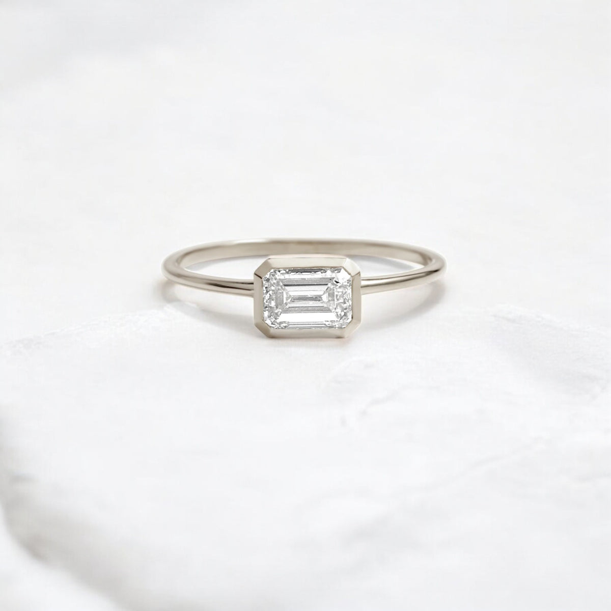 Elegant handmade emerald cut diamond engagement ring, featuring a bezel setting designed for women.