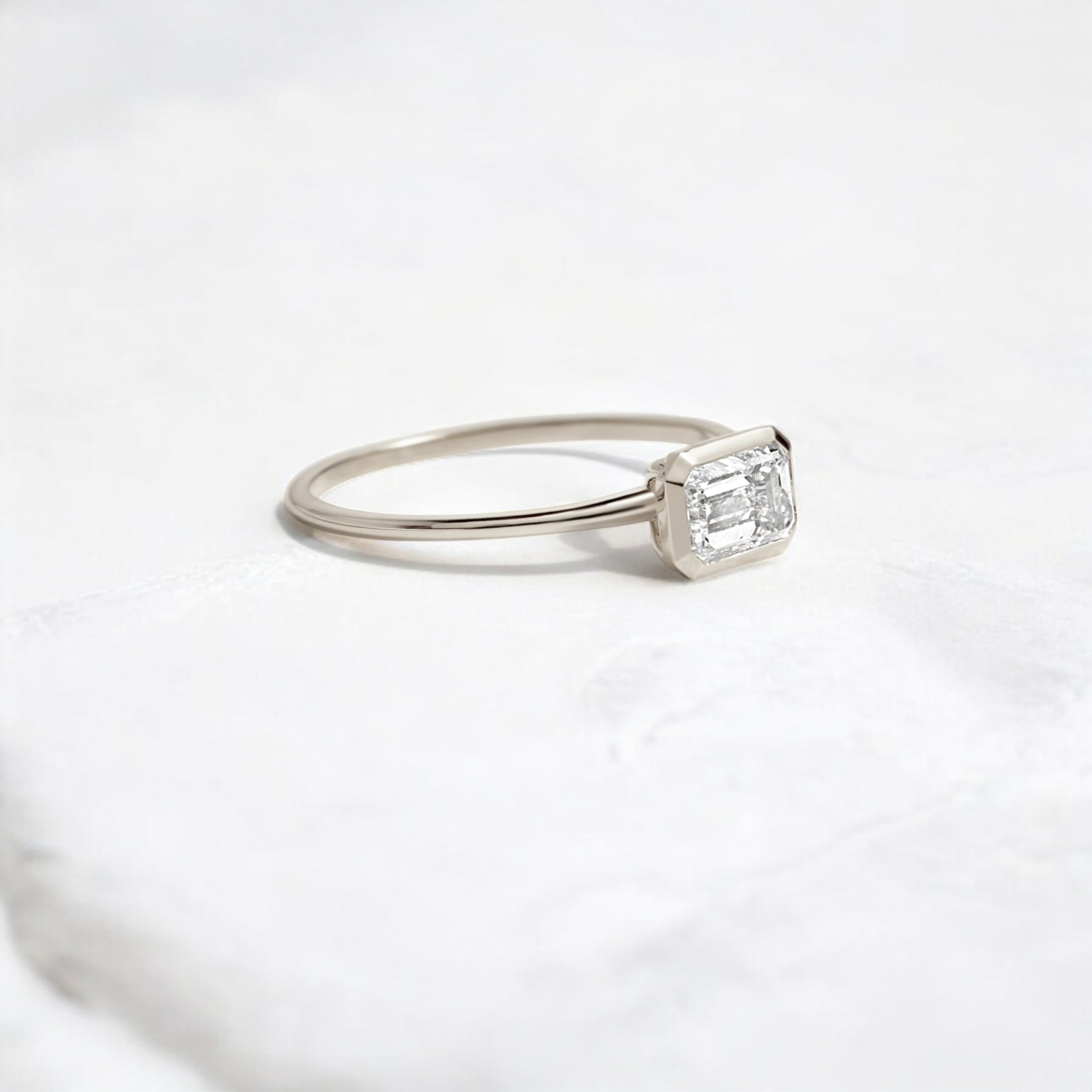Elegant handmade emerald cut diamond engagement ring, featuring a bezel setting designed for women.
