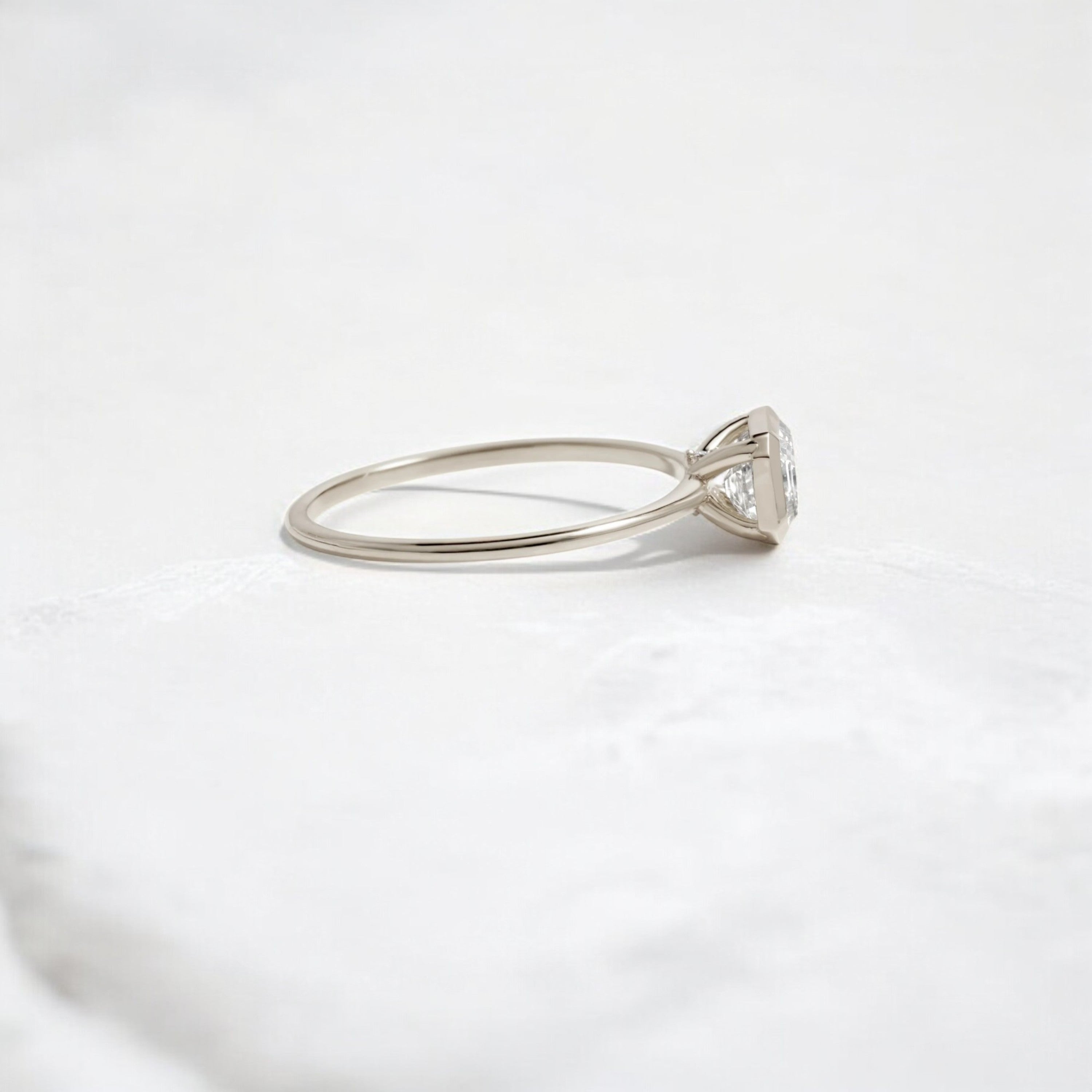 Elegant handmade emerald cut diamond engagement ring, featuring a bezel setting designed for women.