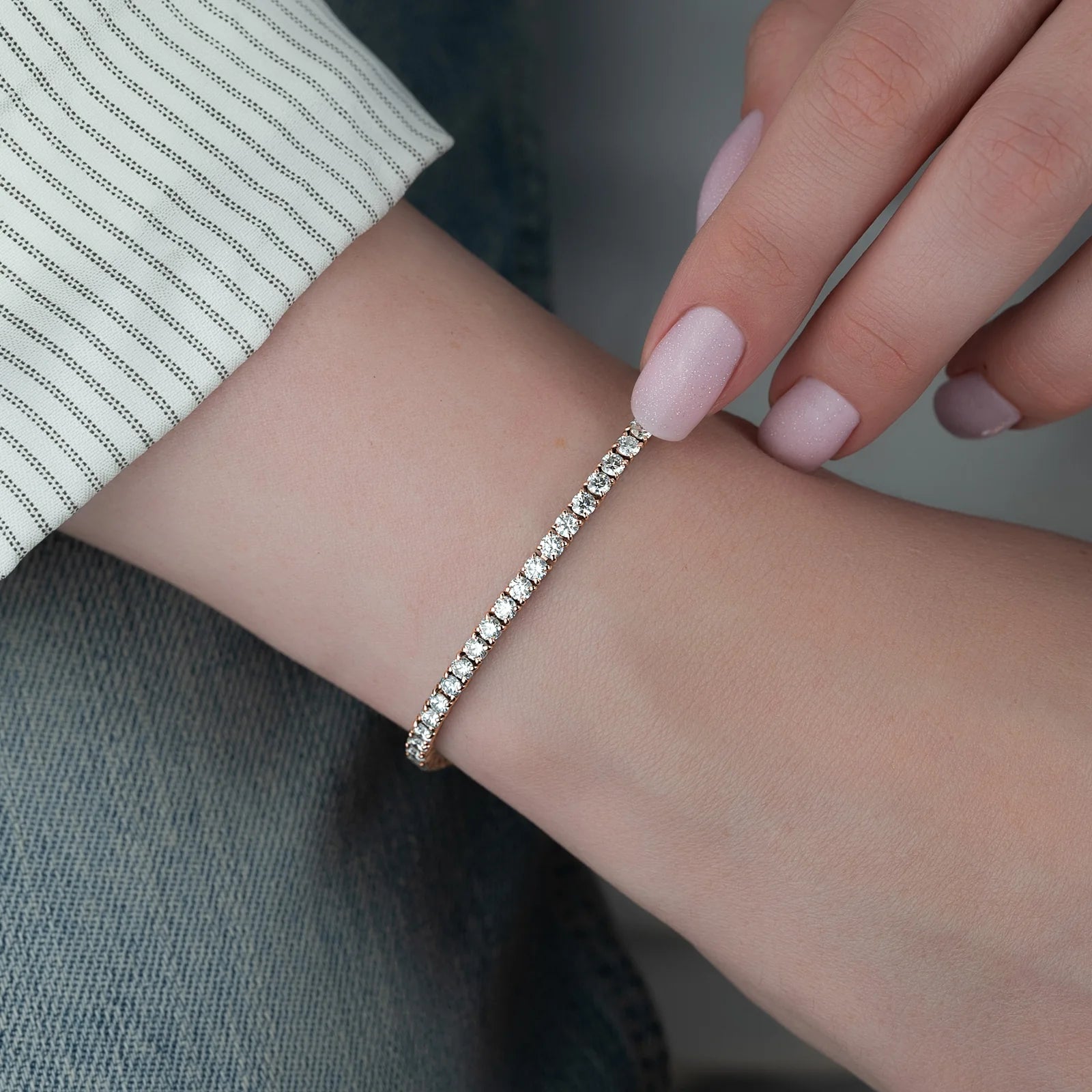 Close-up of a hand wearing a diamond bracelet on a neutral background