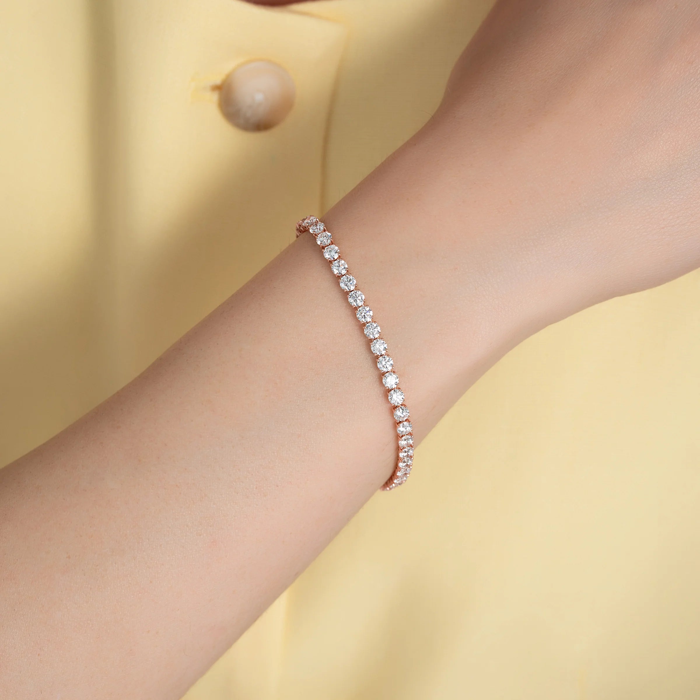 Diamond bracelet on a wrist with a yellow background
